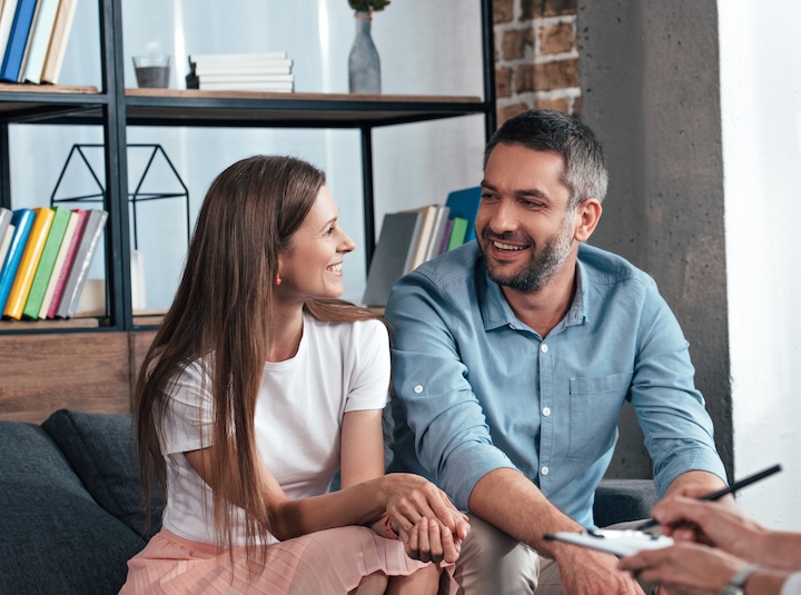 A couple sitting close together and smiling during a therapy session